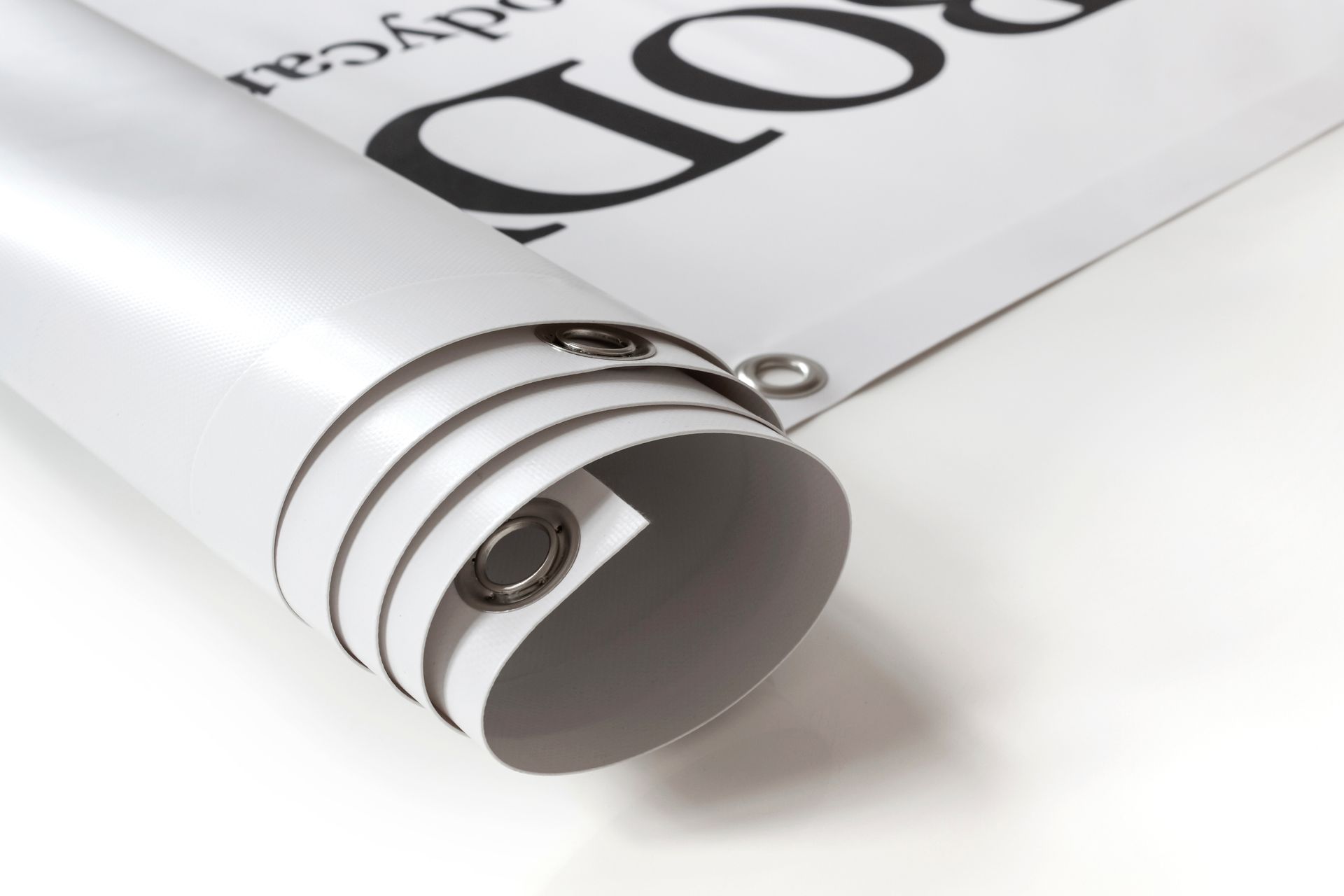 Rolled-up white banner with metal grommets, partially unfurled to reveal large black text on white.