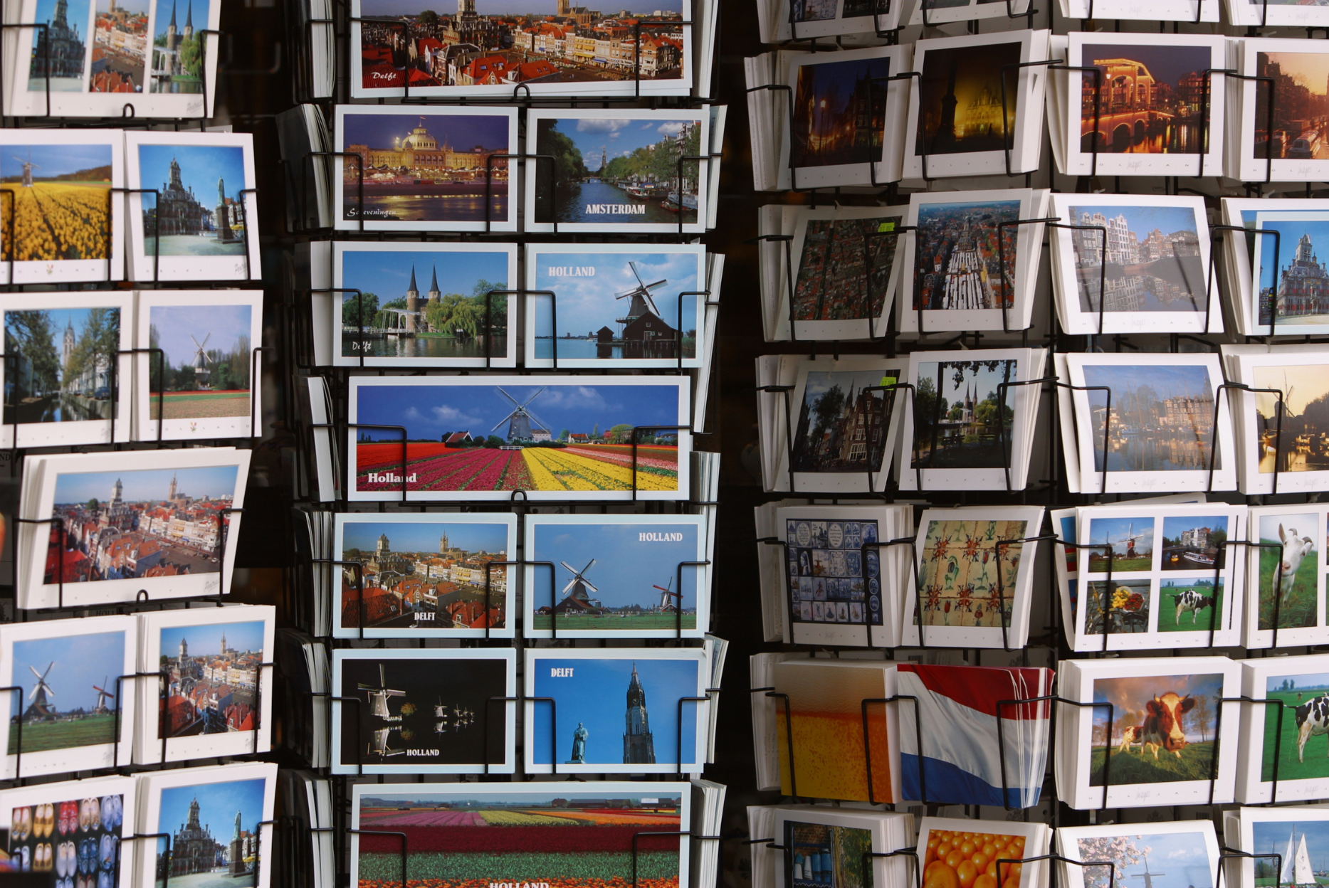 A bunch of postcards are stacked on top of each other on a rack.