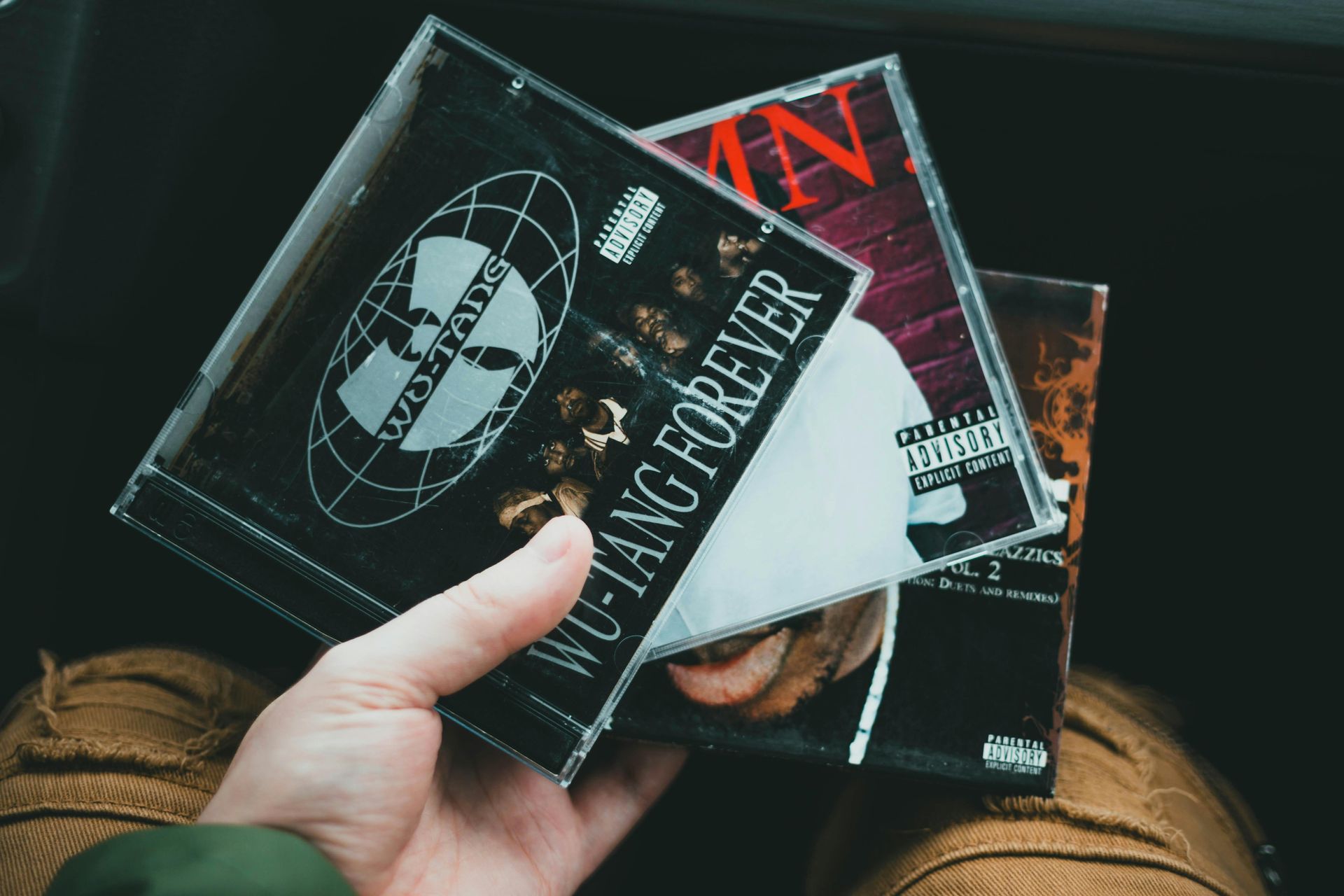 A person is holding a wutang forever cd in their hand.