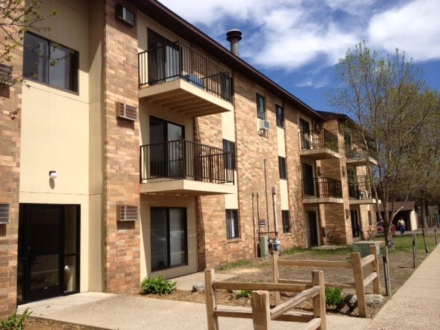 Apartment building with brick exterior, balconies, and small wooden fence.