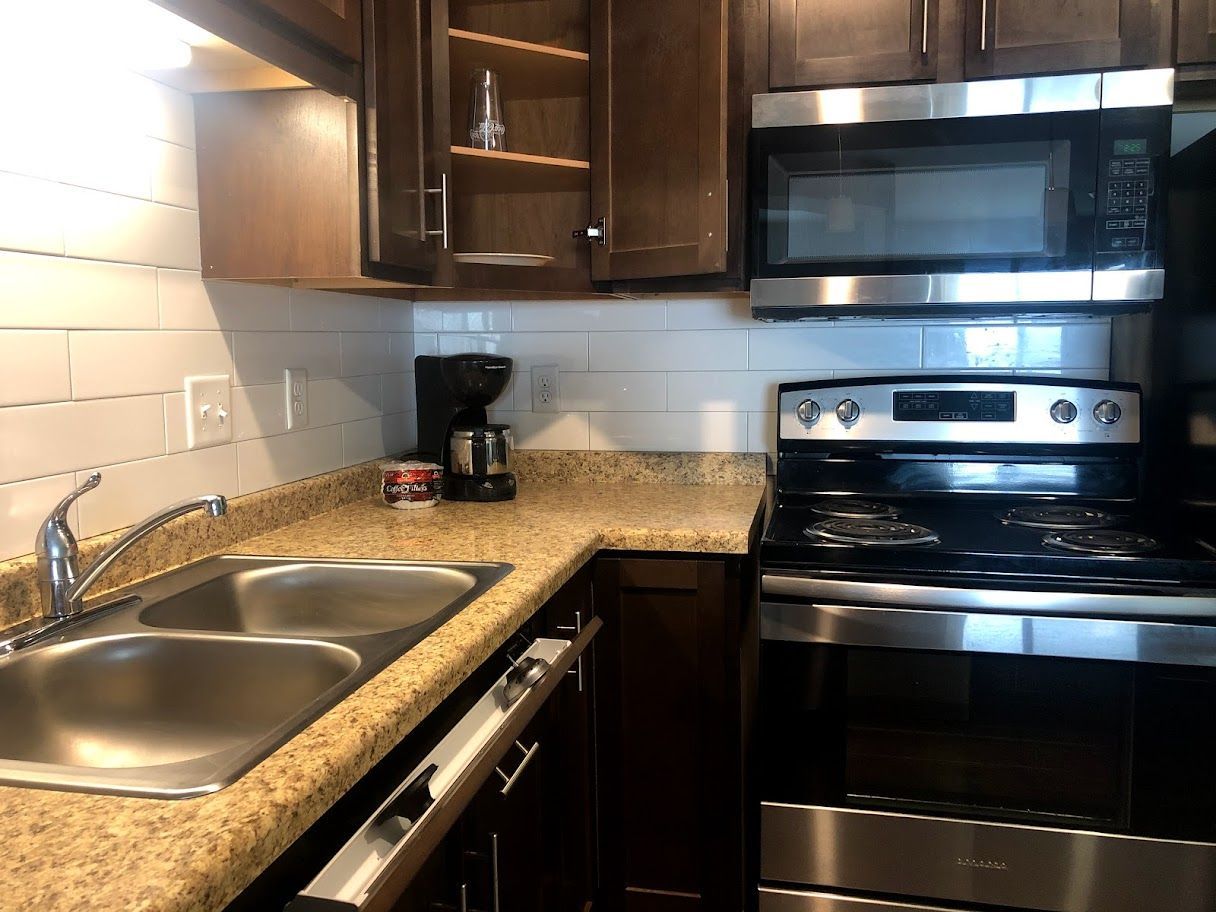 Kitchen with stainless steel appliances, dark brown cabinets, and a double sink.