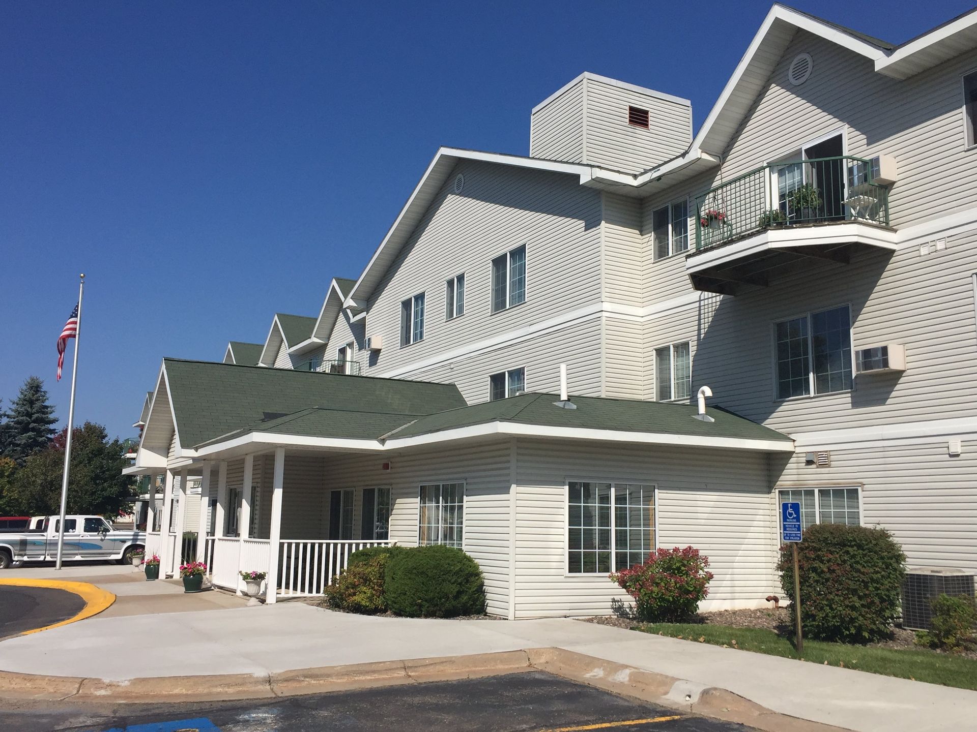 Exterior view of a light-colored multi-story building with a covered entrance; clear blue sky overhead.