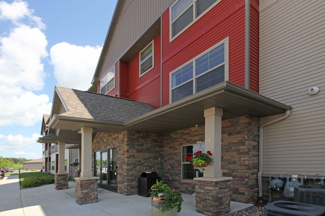 Entrance to a red and tan building with a covered walkway supported by stone columns.