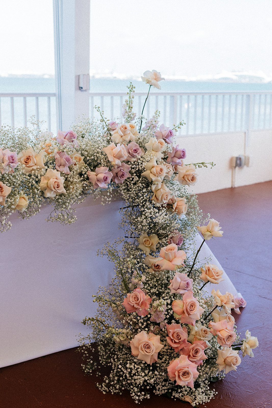 A table with flowers on it in front of a window. A table with flowers on it in front of a window.