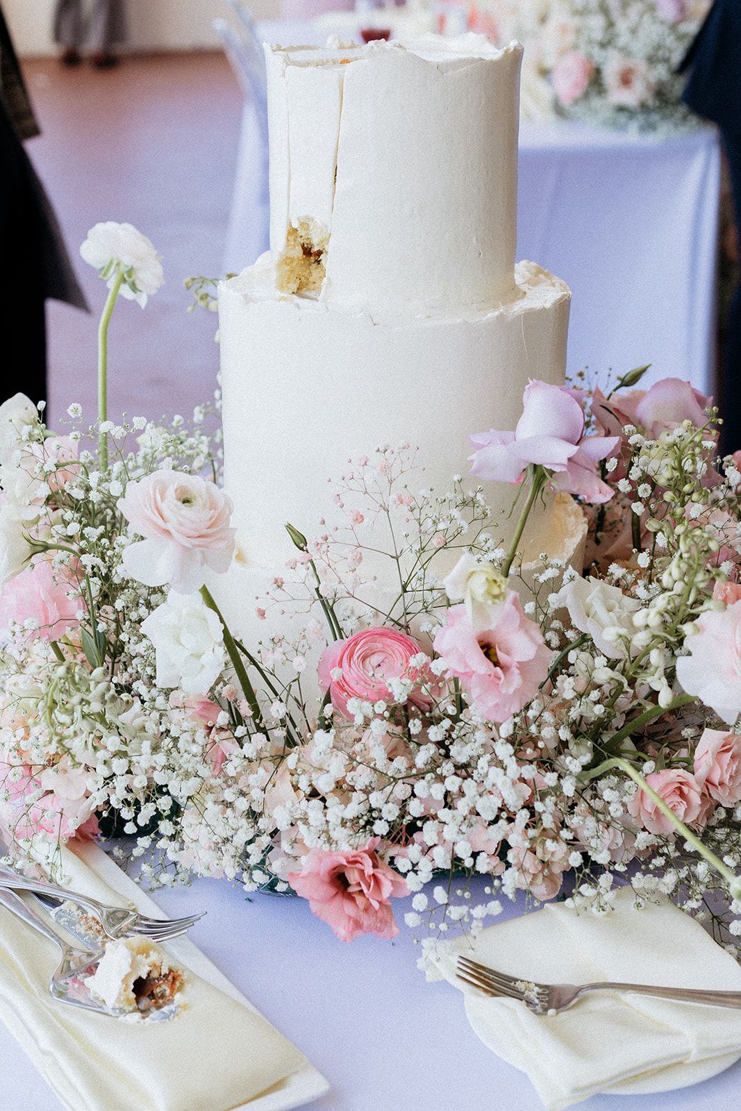 A wedding cake is sitting on top of a table surrounded by flowers.
