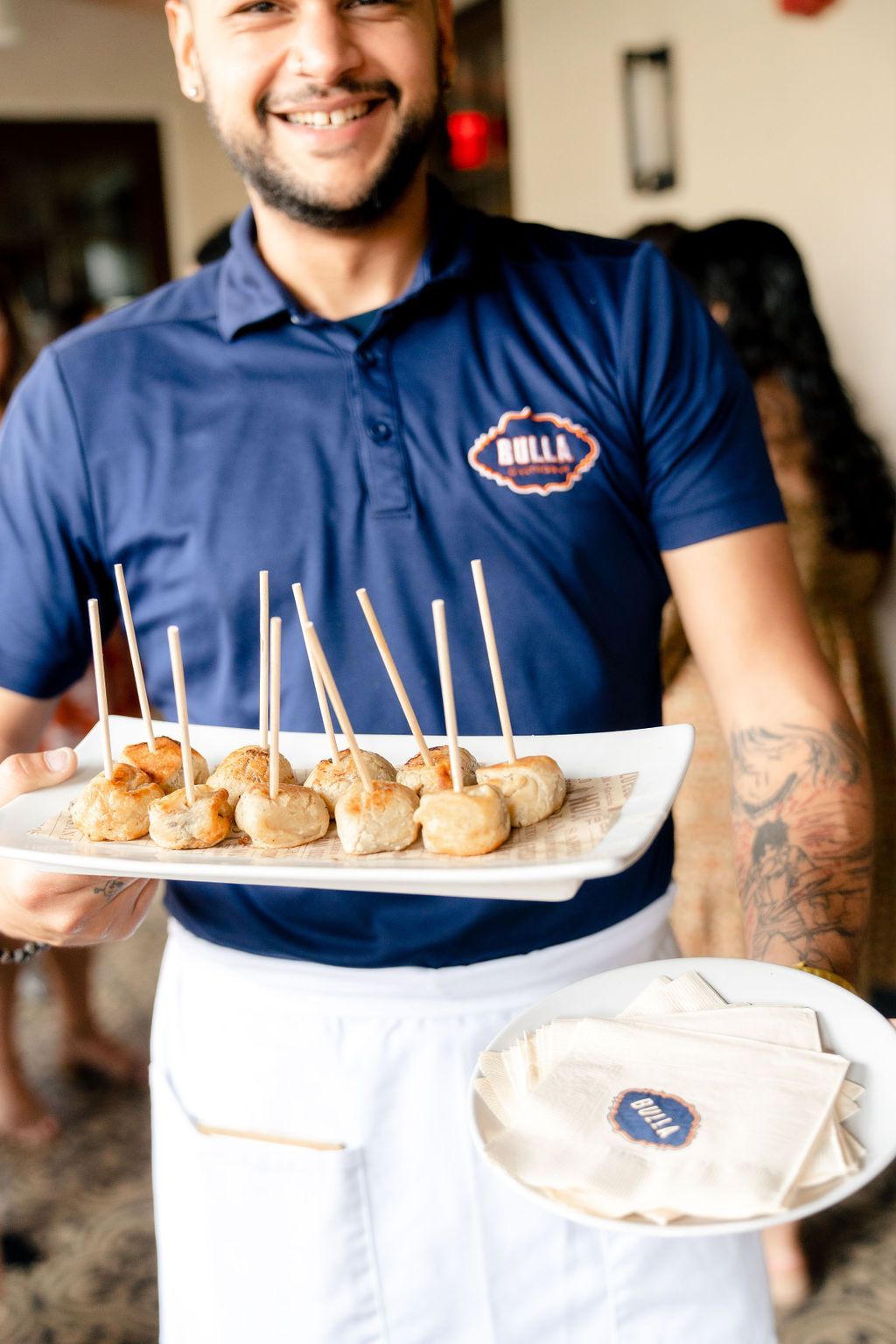 A man in a blue shirt is holding a tray of food. A man in a blue shirt is holding a tray of food.