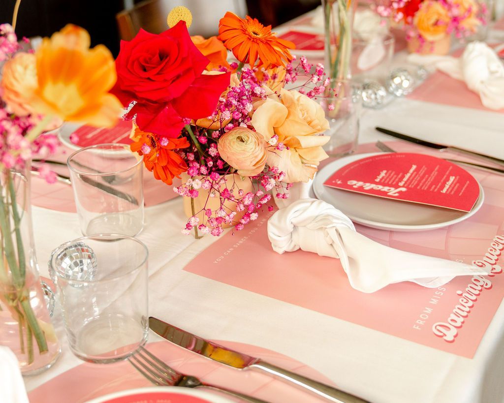 A table with plates, utensils, and flowers on it. A table with plates, utensils, and flowers on it.
