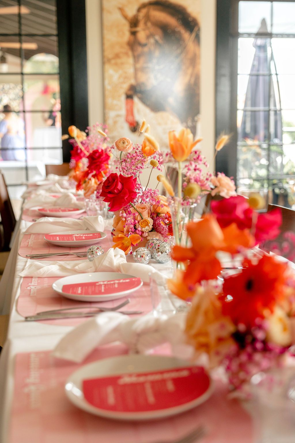 A long table with plates, napkins, and flowers on it.