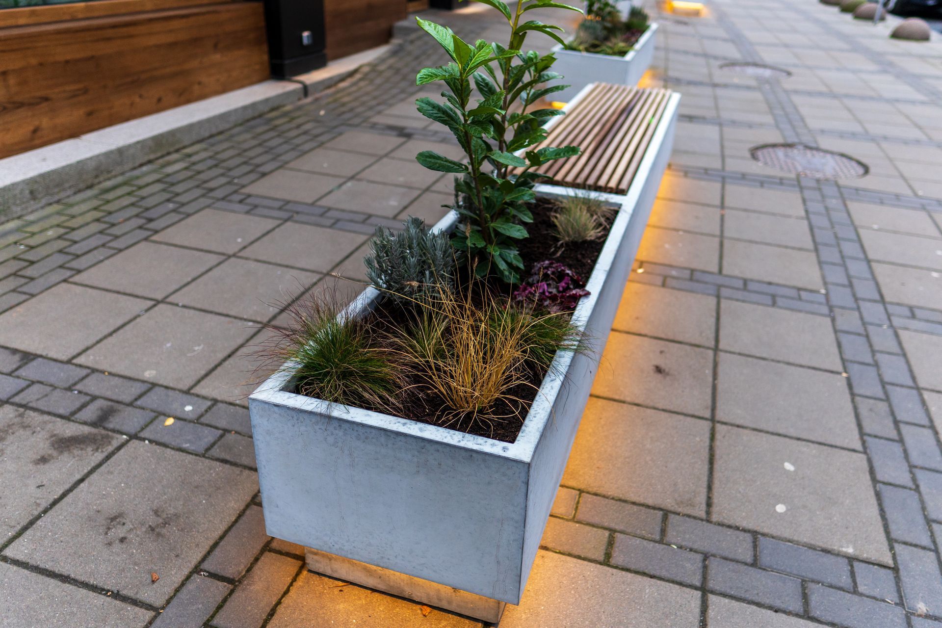 Patio with wicker furniture under a wooden gazebo, surrounded by flowers.