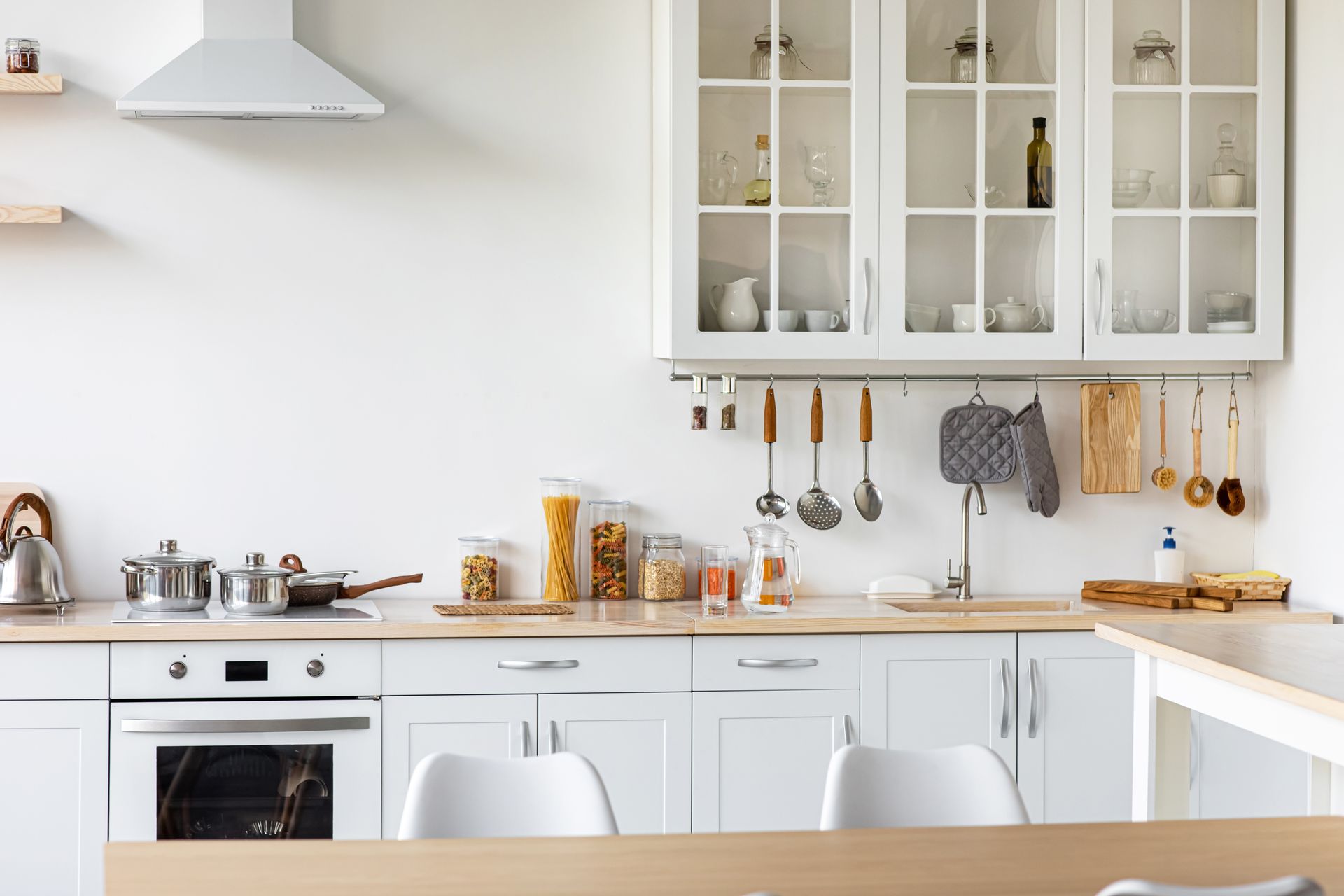 Interior of a home under construction: white walls, wooden staircase, bare floors, and construction tools.