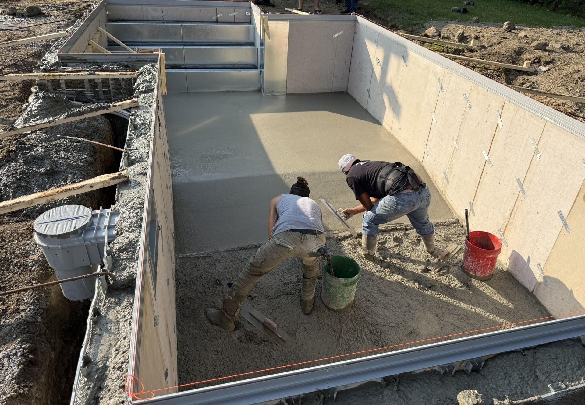 Poolside lounge area with sofas, umbrellas, and a view of trees and the sky.