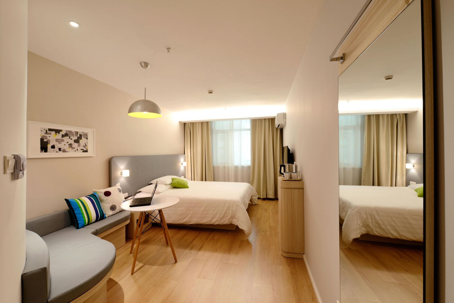 A hotel room with two beds , a couch , a table and a mirror.