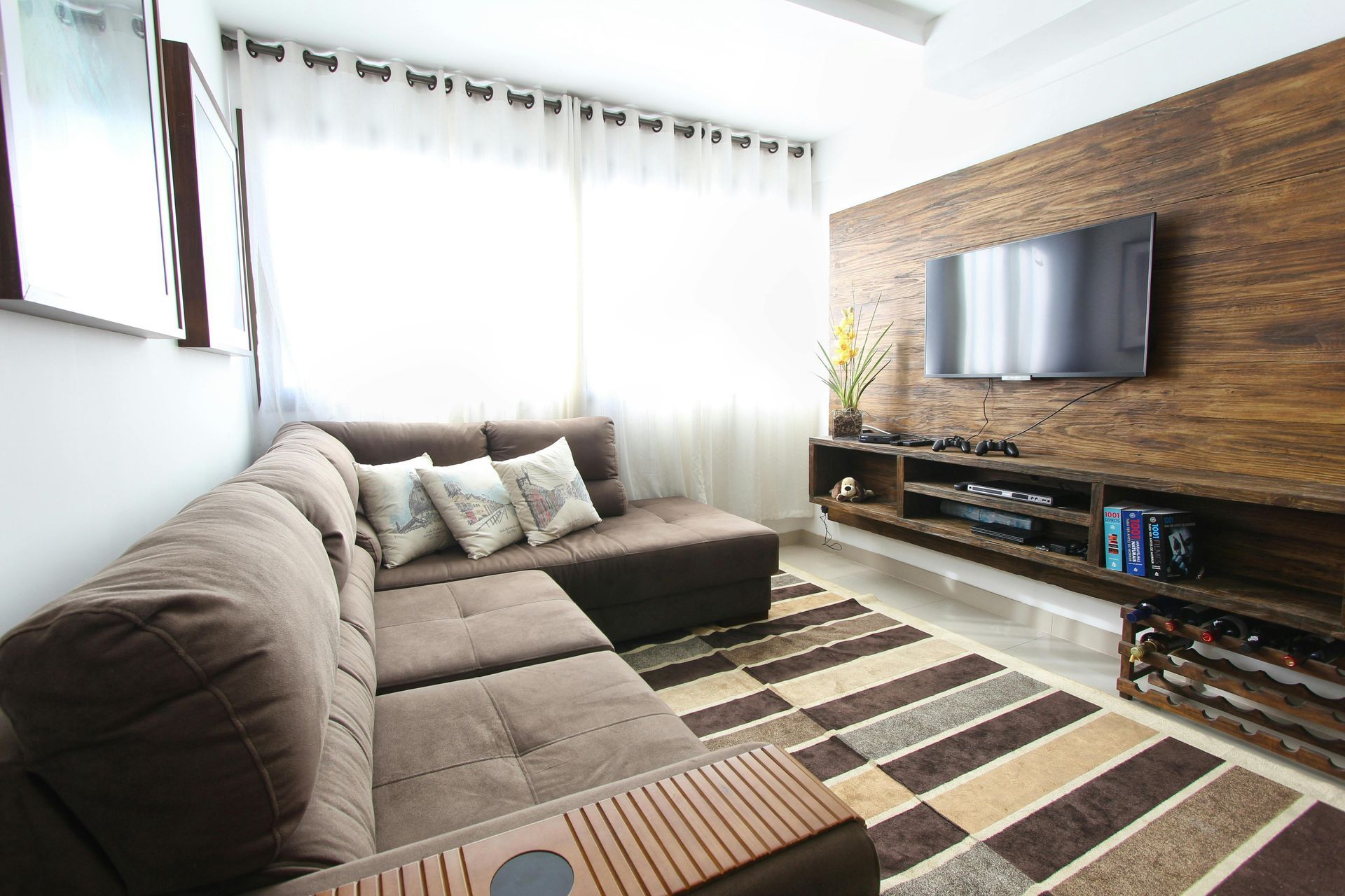 A living room with a couch and a flat screen tv on the wall.