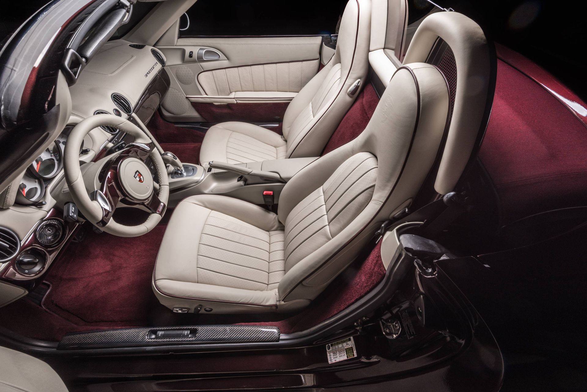 The interior of a red sports car with white seats and a steering wheel.