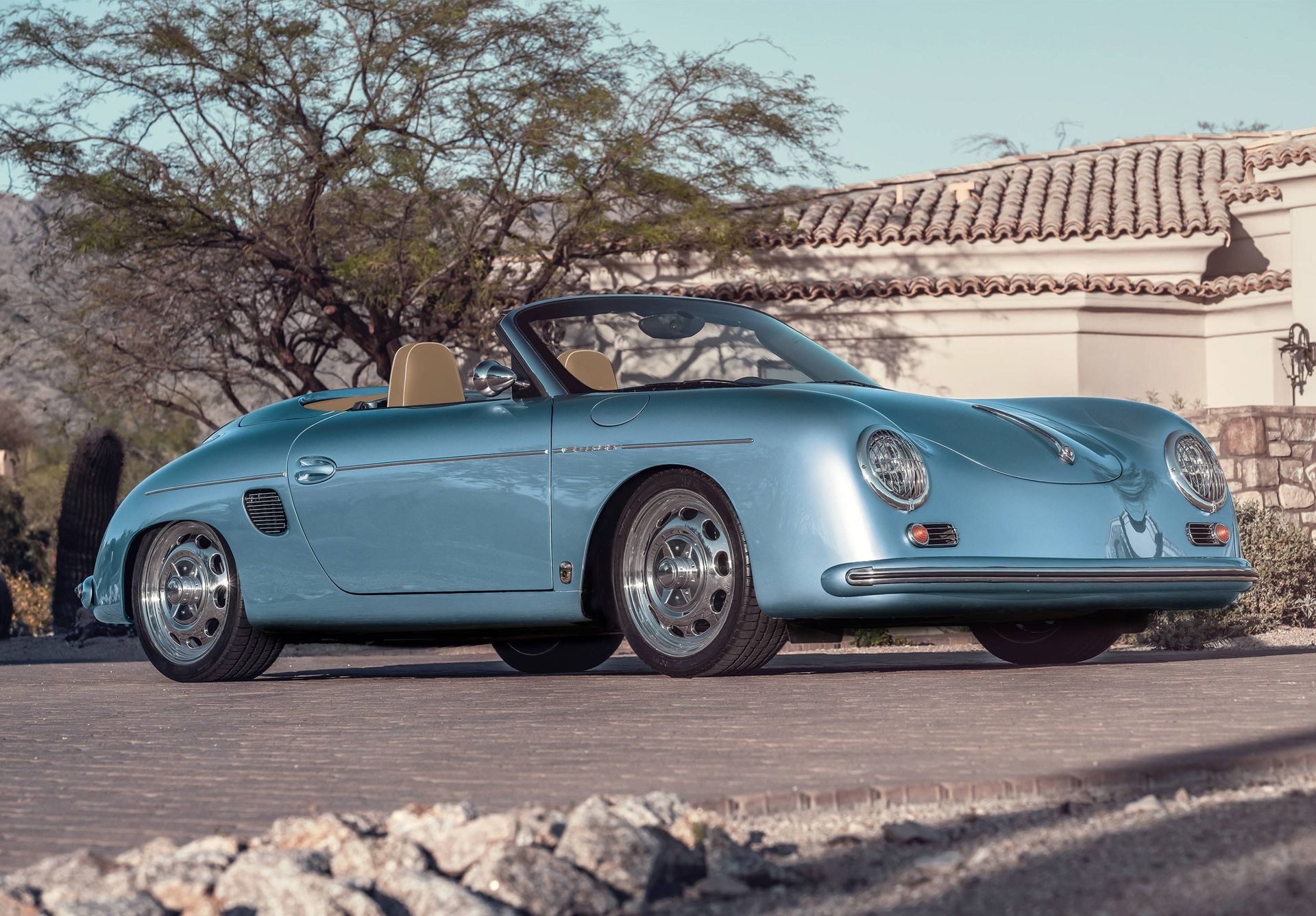 A blue porsche speedster is parked in front of a building.