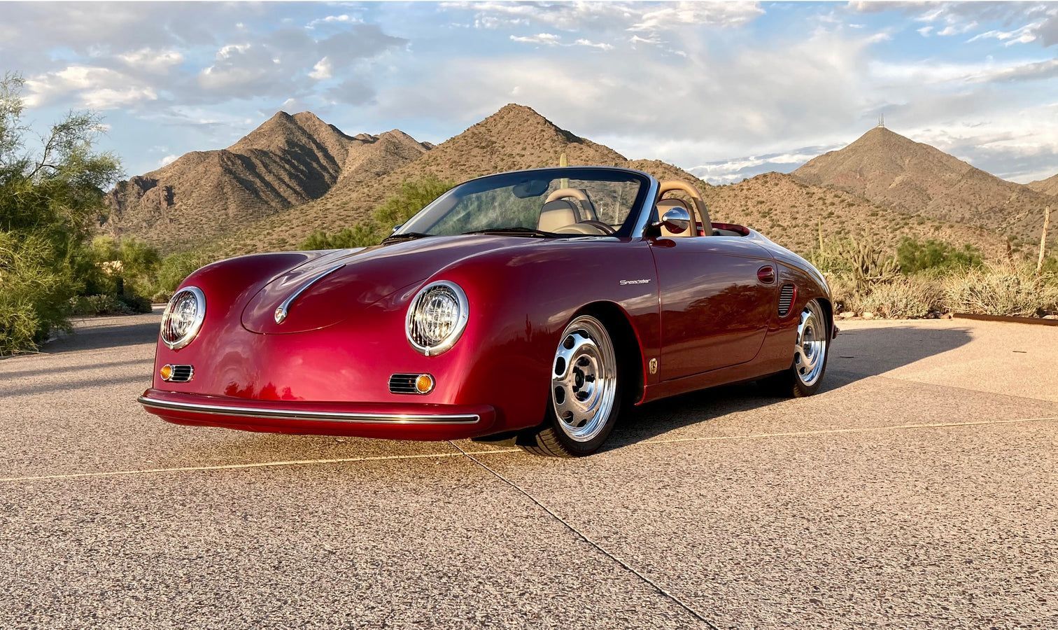 A red convertible sports car is parked on the side of a road.