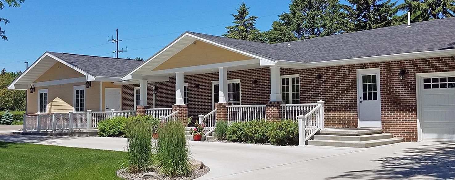 The front door of a house with a porch and plants in front of it.