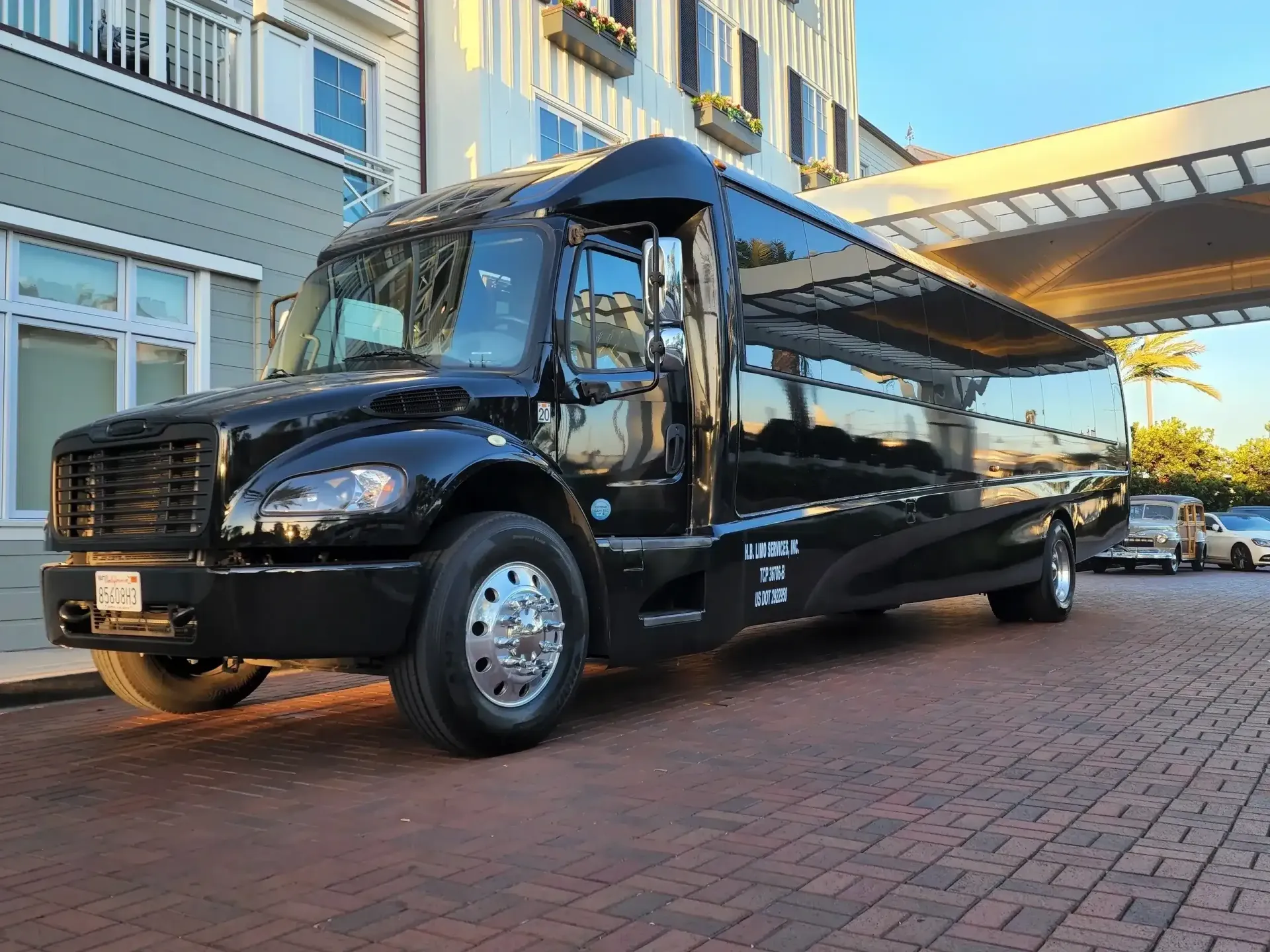 A black limousine is parked in front of a building on a brick street.
