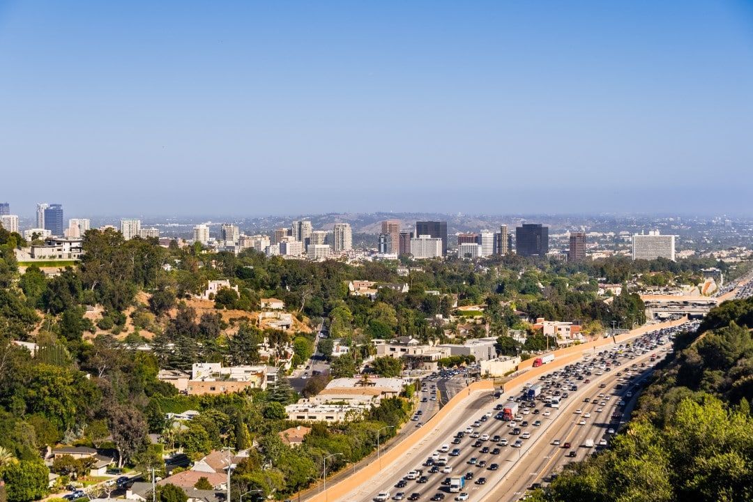 An aerial view of a busy highway with a city in the background.