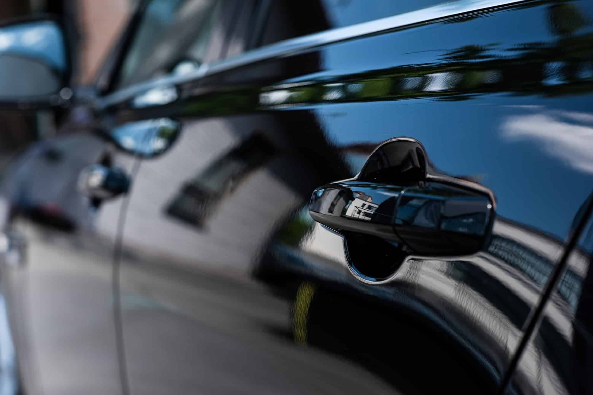 A close up of a car door handle on a black car.