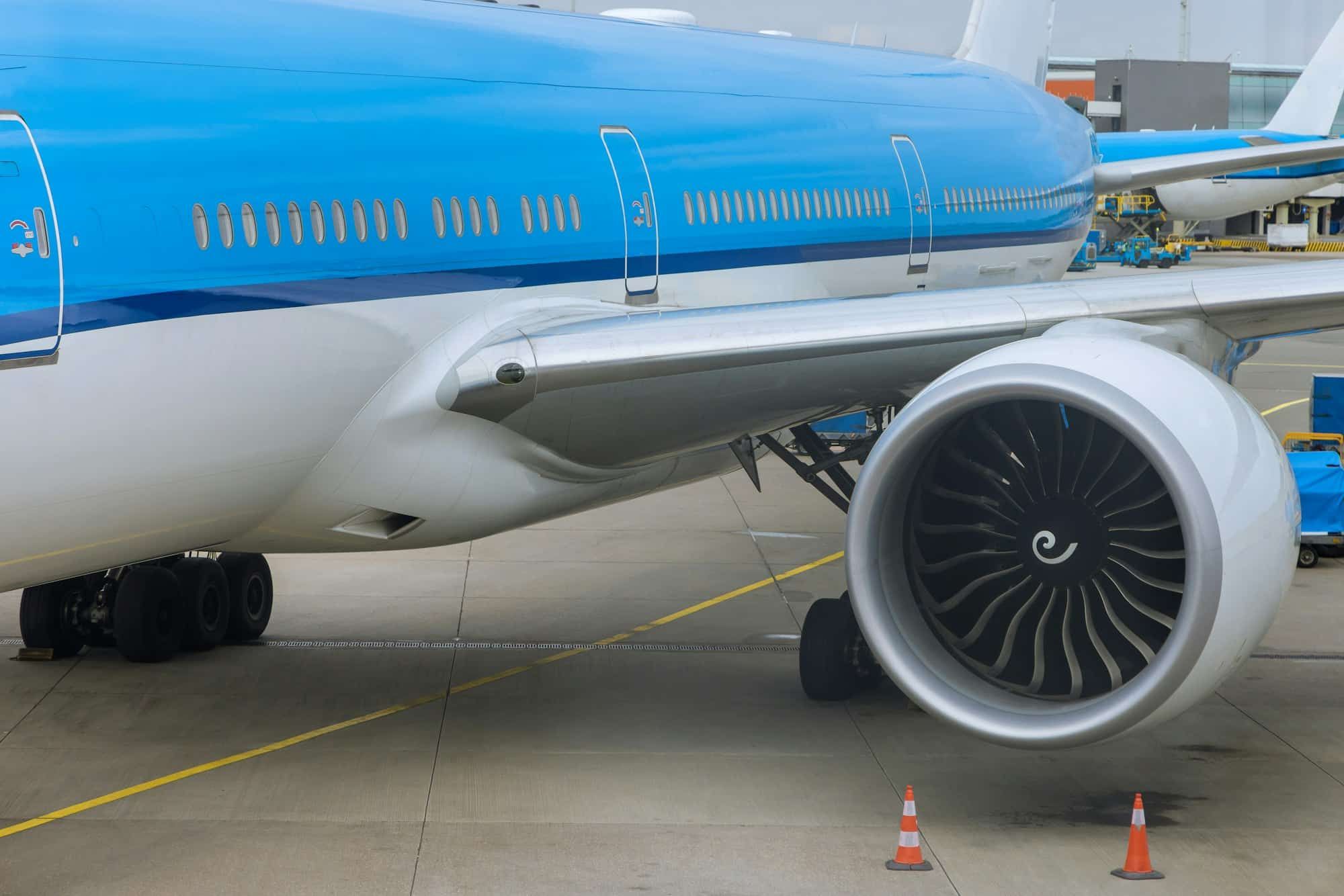 A blue and white airplane is parked on the tarmac at an airport.