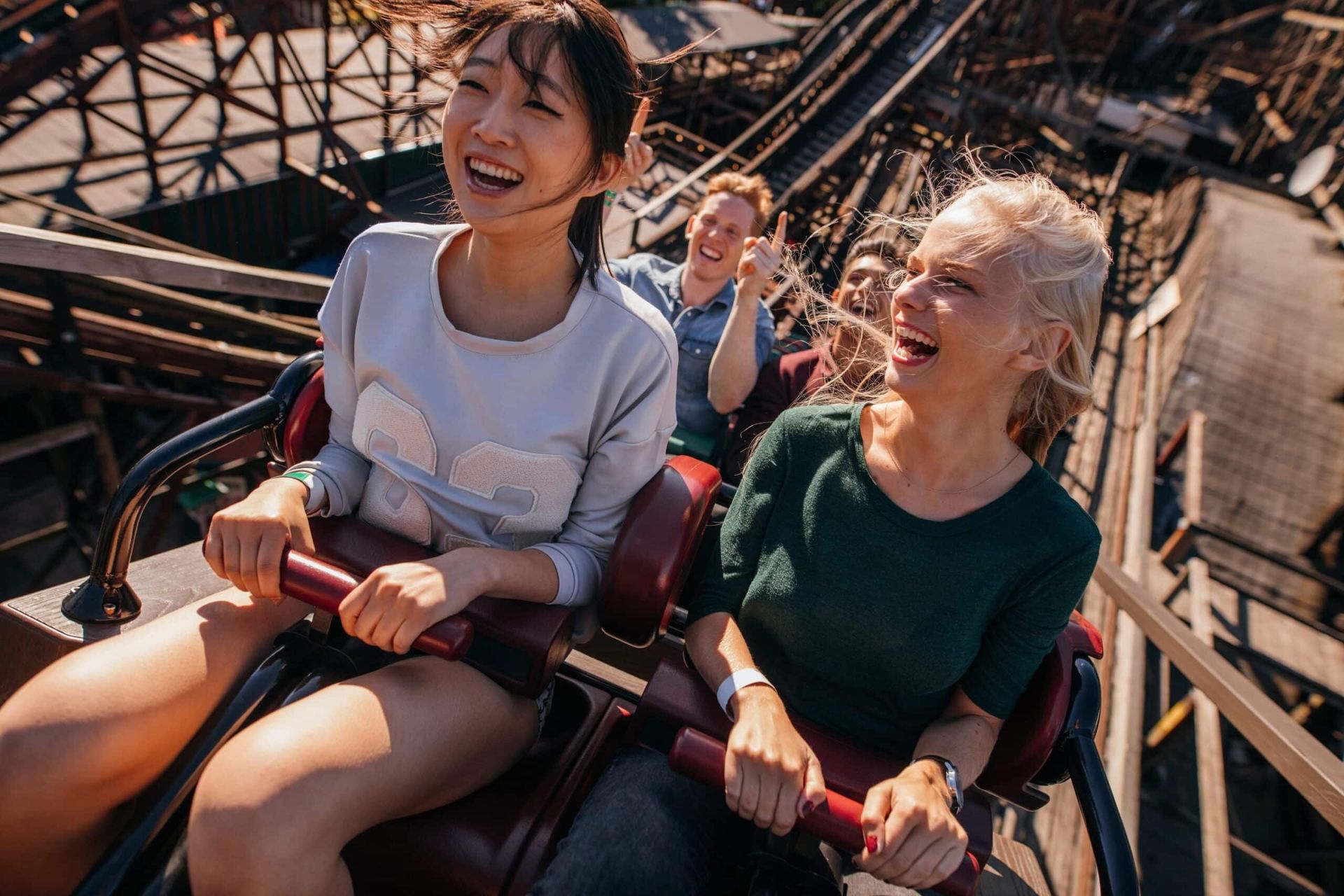 A group of people are riding a roller coaster at an amusement park.