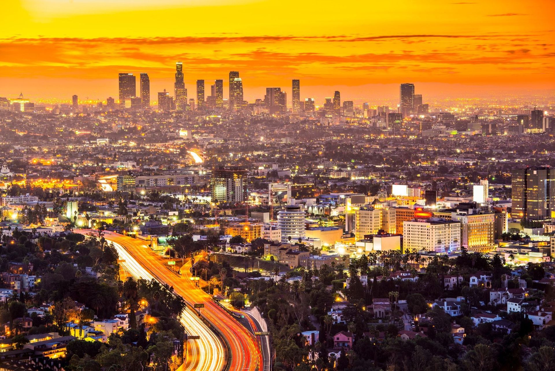 An aerial view of a city at night with a highway in the foreground.