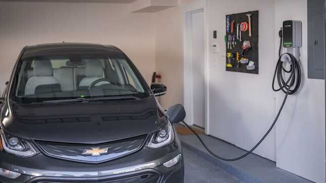A black electric car is being charged in a garage.