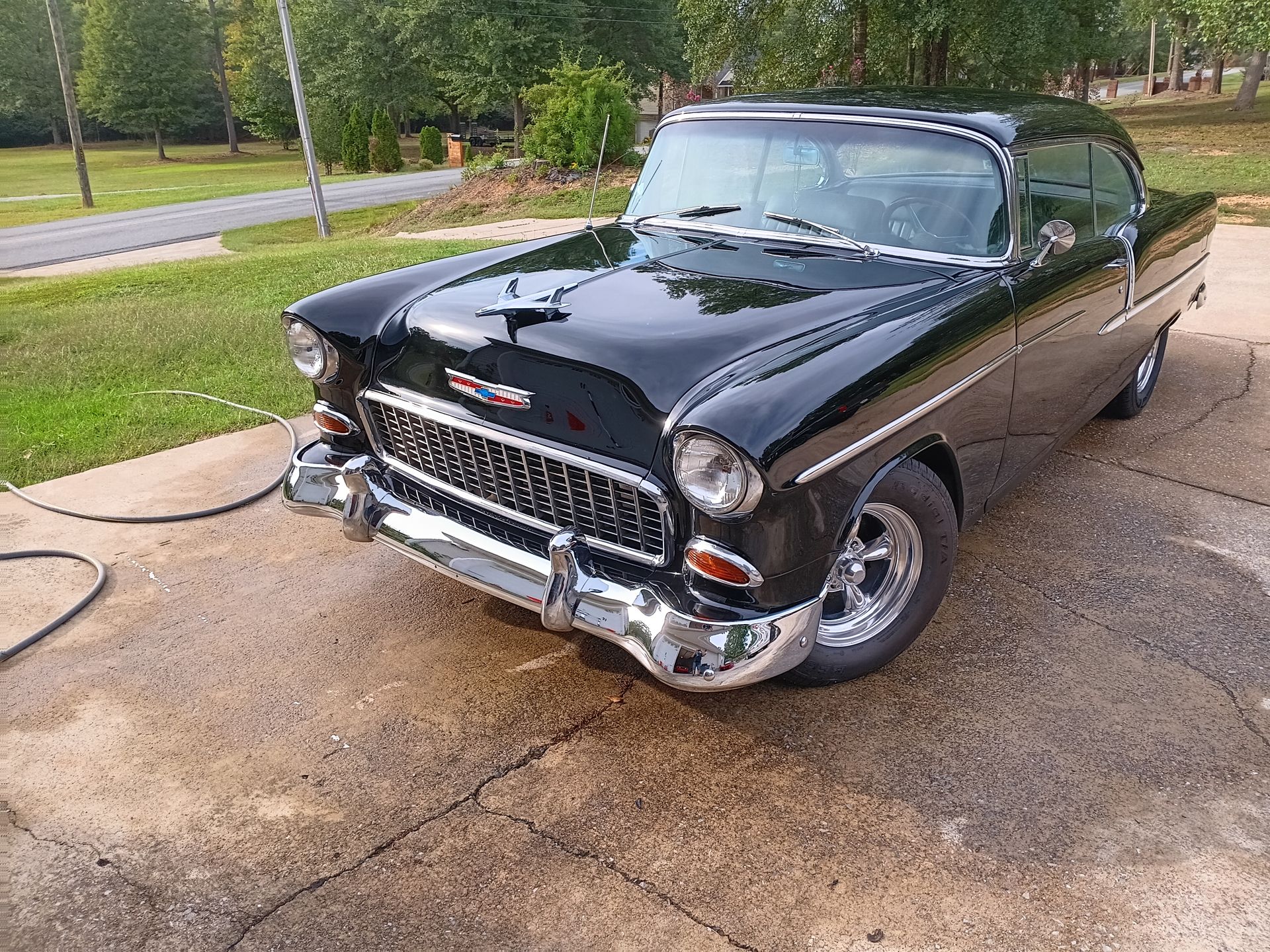 A red pickup truck with bodywork stripped to bare metal around the rear wheel well inside a garage.