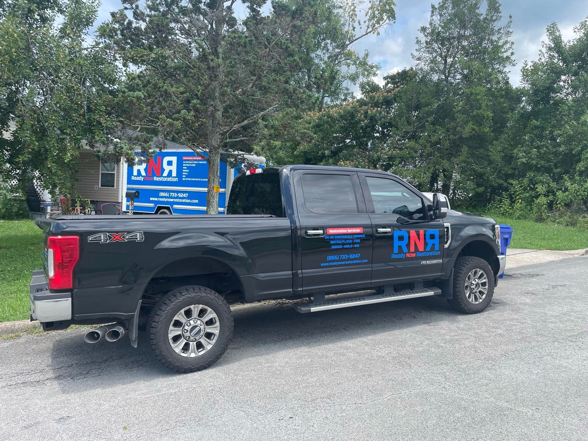 A black truck is parked on the side of the road next to a blue ambulance.
