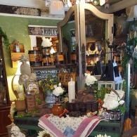 Rustic indoor display with flowers, bottles, and a central mirror under warm lighting
