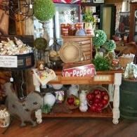 Rustic display of pumpkins, apples, plants, and a Dr Pepper sign in a vintage shop interior