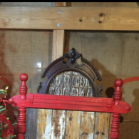 Red wooden chair back in front of a carved arched wooden panel inside a rustic room