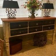 Wooden console table with lamps and flowers in a sunlit room