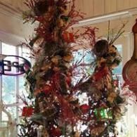 Festive indoor display with tall floral arrangements and red, brown, and white decorations near windows