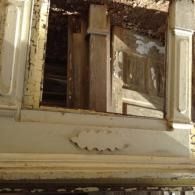 Open, damaged wooden window shutters on a worn beige building facade