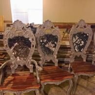 Three ornate wooden chairs with carved backs in a warmly lit room