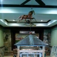 Indoor display room with a horse statue suspended above a central exhibit case.