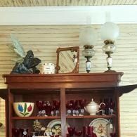 Decorative glass and ceramic items displayed on top of a wooden cabinet against a beige wall