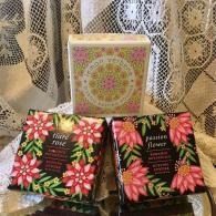 Three floral gift boxes on a lace curtain backdrop, with pink and black packaging and pastel center box