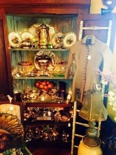 Antique cabinet with decorative dishes, fruit bowl, and a mannequin in a vintage shop display