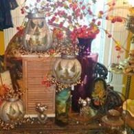 Decorative fall display with pumpkins, flowers, and candles arranged on a table in a warm indoor setting