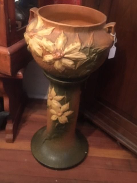 Decorative ceramic pedestal planter with painted flowers, in tan, green, and gold on a hardwood floor