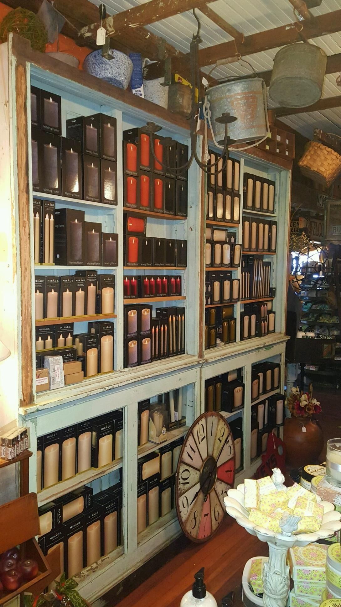 Rustic shop wall with shelves of bottles, jars, and ceramics, lit warmly inside a narrow aisle