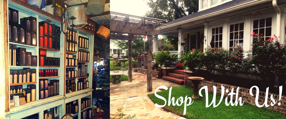 Boutique storefront with colorful books on display beside a garden patio and “Shop With Us!” text