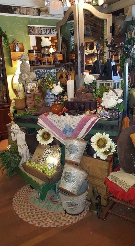 Decorative indoor display with flowers, pottery, and colorful crafts in a cozy shop or garden setting
