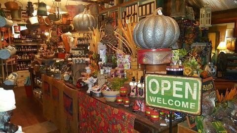 Colorful shop interior with ornate decor and a green “OPEN” sign near the counter.
