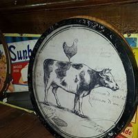 Vintage tin plate with a cow and rooster illustration on a shelf