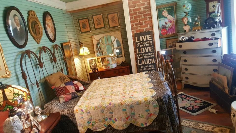 Cozy bedroom with floral bedspread, wicker decor, wall art, and warm lamp light