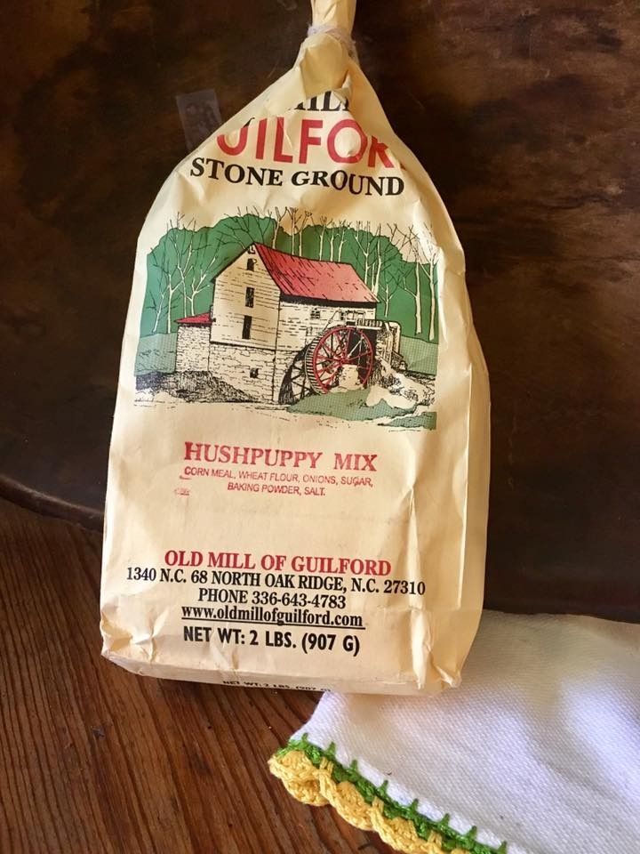 Bag of Guilford Stone Ground Hushpuppy Mix on a wooden table beside a white cloth.